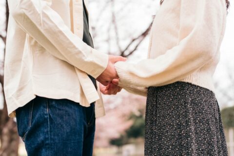 向き合って両手を繋ぐカップル