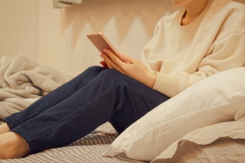 ベッドでスマホを操作する女性